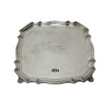 A silver salver, of shaped square form, raised on four corner feet, in the 18th century taste,
