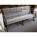 A 19th century garden bench, with slatted wood seat on naturalistic cast iron supports,