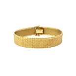 A gold bracelet of wide interwoven link form, having a textured finish, on a snap clasp,