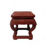 A Chinese carved cinnabar lacquer stool, 20th century decorated all over with dragons, 38cm high.