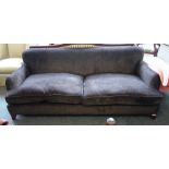 A 20th century brown upholstered three seat sofa, on tapering block supports,