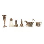 A pair of Sterling pepper casters, each raised on three lion mask and pad feet, a sauceboat,