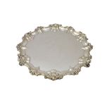 A silver salver, of shaped circular form, with a decorated pie-crust rim, having floral motifs,