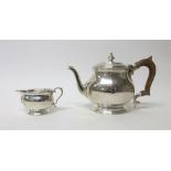 A silver teapot of oval form, the hinge lid with a turned finial, raised on an oval foot,