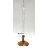 A glass Geissler tube, with internal clear and green glass filaments, on a turned wooden base,