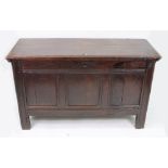 A late 17th century oak coffer, of panelled construction, with hinged top, on extended stiles,