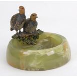 A circular green onyx dish, mid 20th century, surmounted by two cold painted figures of partridge,