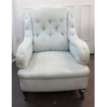 A late Victorian button down upholstered armchair, on turned legs and castors.