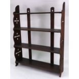 A set of late Victorian carved oak narrow three tier wall hanging shelves, with mask capitals,