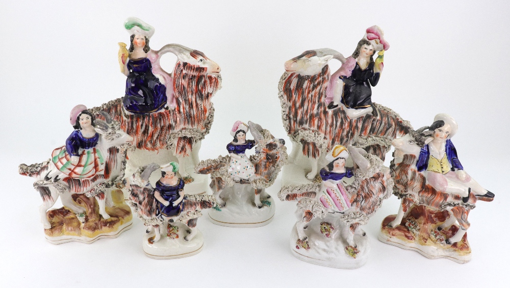 A pair of Staffordshire figures of children kneeling on goats and holding birds,