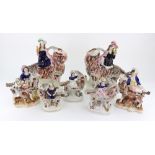 A pair of Staffordshire figures of children kneeling on goats and holding birds,