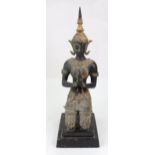 A Thai bronzed and gilded kneeling figure in prayer, on a stepped ebonised base, 52cm high.