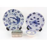 Two Delft blue and white plates, one painted with pheasants beneath trees, the other flowers,