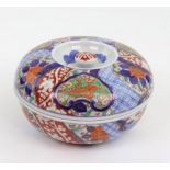 A Japanese Imari circular bowl and cover, painted with segmented floral panels and diaper,