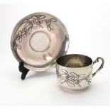 A French Art Nouveau silver tea cup and saucer, with raised flowering mistletoe decoration,