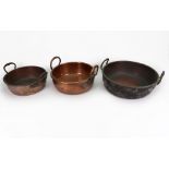 A collection of three Victorian copper and brass preserve pans, each with twin raised side handles,