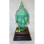 A green glazed head of Buddha, modelled with eyes close and serene expression,