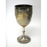 A silver trophy cup, embossed with fruiting vine, raised on a circular foot,