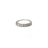 An eleven stone diamond half hoop eternity ring, claw set in white metal, stamped '18ct',