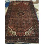 A Hamadan rug, Persian, the madder field with a black medallion, herate pattern, ivory spandrels,