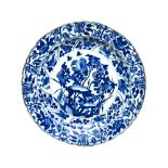 A Chinese blue and white dish, Kangxi, painted in the centre with flowering shrubs and rocks,