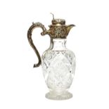 A silver mounted faceted glass hinge lidded claret jug, of vase shaped form, the mount with floral,