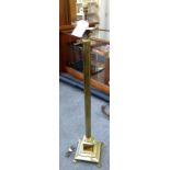 A brass standard lamp formed as a reeded Corinthian column, on a square stepped base with paw feet,