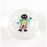 A John Deacons glass paperweight with a central Golliwogg in a glittered striped green jacket,