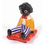 A Clarice Cliff, Wilkinson, seated Golliwogg bookend, on an orange cushion,