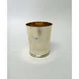 A silver beaker, of tapered cylindrical form, raised on a circular foot, gilt within, height 9cm,