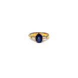A gold, sapphire and diamond three stone ring, claw set with the oval cut sapphire at the centre,
