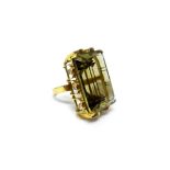 A gold ring, claw set with a large cut cornered rectangular step cut smoky quartz at the centre