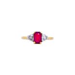 An 18ct gold, ruby and diamond three stone ring, claw set with a central cushion cut ruby,