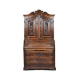 An 18th century German carved oak bureau cabinet, the scroll cornice over a pair of doors,