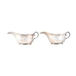 A pair of Scottish silver sauceboats, each with a scrolling handle raised on an oval foot,