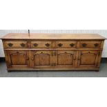 An 18th century style oak dresser base, with four drawers over four arched panel cupboards,