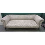 A Victorian Chesterfield sofa, with rollover arms on turned ebonised supports,