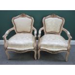 A pair of Louis XV style cream painted parcel gilt open armchairs,