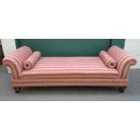 A large 20th century day bed, with double rollover ends, on squat sabre supports,