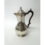 A Victorian silver hot water jug, of plain baluster form, with an ebony handle, London 1866,