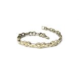 A white gold and diamond bracelet, in a twistover and tapered link design,