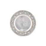 A silver circular dish, having a wide rim, embossed with floral and foliate swags,