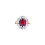 An 18ct gold, ruby and diamond oval cluster ring, claw set with the oval cut ruby at the centre,