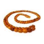 A single row necklace of graduated oval vary coloured butterscotch coloured amber beads,