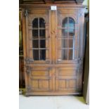 A 20c carved oak bookcase/display cabinet with two glazed doors over two panelled doors (one small