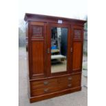 An Edwardian walnut compactum wardrobe with central mirror door flanked either side by hanging