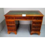 A late 20c yew wood pedestal writing desk with a green tooled leather (one handle missing) est: