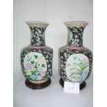 A pair of large modern Chinese vases of squared design decorated with panels of flowers on a black