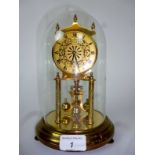 A decorative gilt metal mantle clock with engraved dial and rotating pendulum under a glass dome