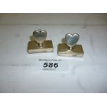 A pair of silver heart shaped menu holde